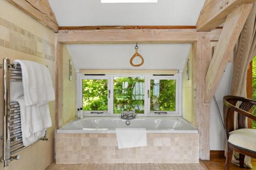 a bath tub in a bathroom with a window at Barberry Brook - Swimming pool acces in Dittisham