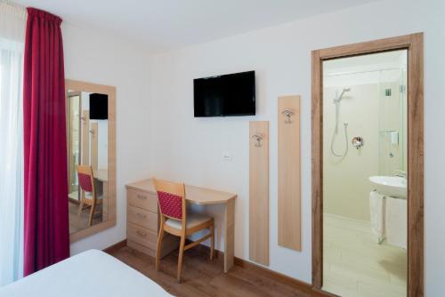 a bedroom with a desk and a bathroom with a shower at Garni Val Udai in Mazzin