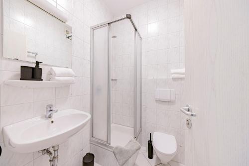 ein weißes Badezimmer mit Waschbecken und Dusche in der Unterkunft Hillerts Hotel in Rheda-Wiedenbrück