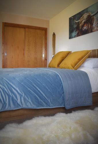 a large bed with a blue blanket on top of it at Benview House in Staffin