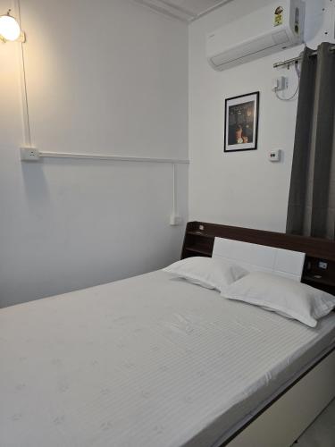 a bedroom with a bed with white sheets and a window at Camellia The Bungalow in Dibrugarh