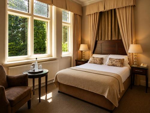 a bedroom with a large bed and two windows at Macdonald Frimley Hall Hotel & Spa in Camberley