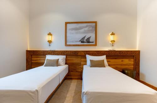 two beds in a room with a picture on the wall at Halisi Villas in Nungwi