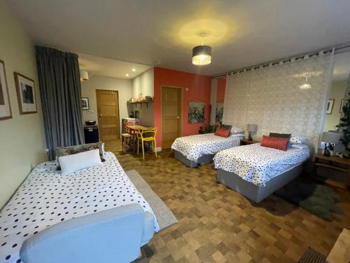 a room with two beds and a kitchen with a table at "The Studio" Contemporary studio with organic swimming pool in Skelsmergh