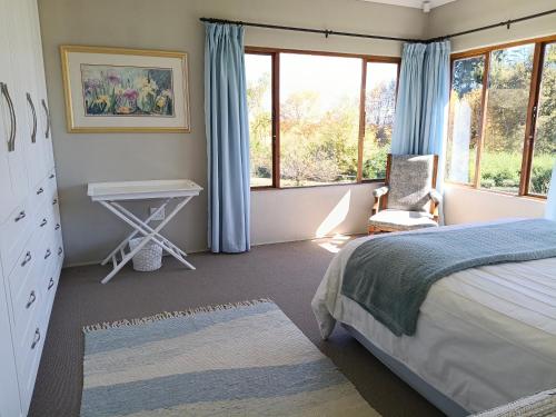 a bedroom with a bed and a desk and windows at Valley View the home with a view in Nottingham Road