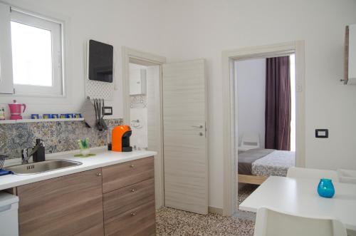 a white kitchen with a sink and a bedroom at Donna Nunzia Home in Noto
