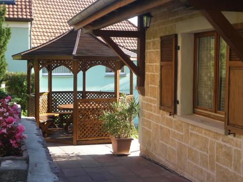 a wooden gazebo on the side of a house at Ferme du Mouton Noir in Lautenbachzell
