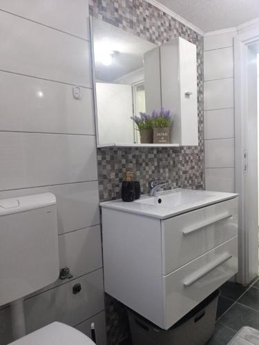 a white bathroom with a sink and a mirror at Apartment Alan - Modern Stay in Travnik