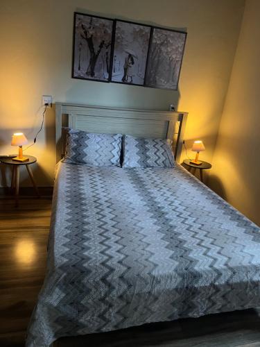 a bedroom with a bed with two lamps on two tables at Chalé com lareira externa e vista para o Pico do Lopo in Extrema