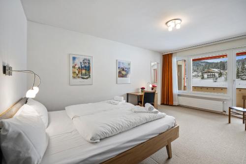 a white bedroom with a large bed and a window at Triangel A Freund in Parpan