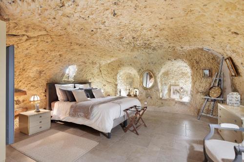 a bedroom with a bed in a stone wall at Les Iris - Maison Troglodytique in Trôo