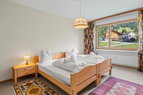 a bedroom with a bed with white sheets and a window at Triangel D Grossenberger in Parpan