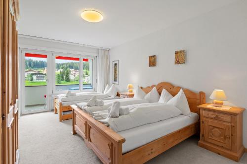 a bedroom with two beds and a large window at Triangel B Rezia in Parpan