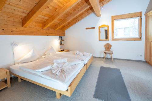 a bedroom with a large white bed with a wooden ceiling at Clois B Loughlin in Lenzerheide