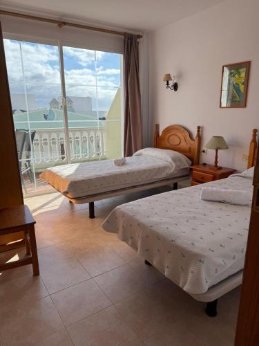 a bedroom with two beds and a large window at VV Monica 33 "by AFCVacacional" in Puerto Naos