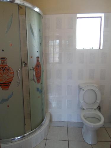 een badkamer met een toilet en een glazen douche bij Hardrock Guest House in Francistown
