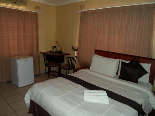 una camera d'albergo con un grande letto con cuscini bianchi e neri di Hardrock Guest House a Francistown