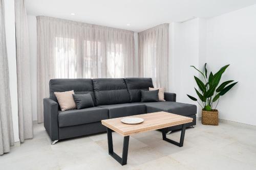 a living room with a black couch and a coffee table at Sunrise Center Suites in Torrevieja