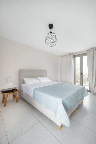 a white bedroom with a large bed and a window at DION APARTMENTS in Paleros
