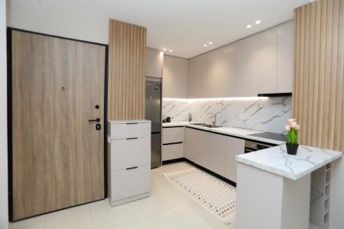 a kitchen with white counters and a large wooden door at Alrei Apartment in Vlorë