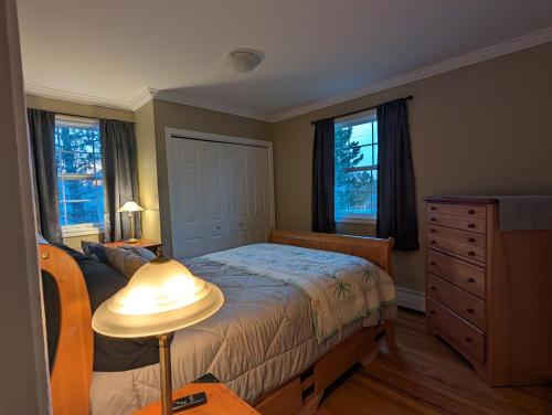 a bedroom with a bed and a dresser and windows at St Andrews Guest Home in St. John's