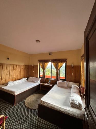 a bedroom with two beds and a large window at Berg House Cafe and Hotel in Nagarkot
