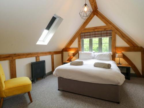 a bedroom with a bed and a yellow chair at Gayton Stables in Wirral