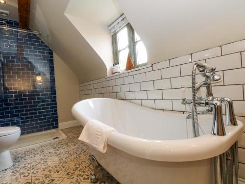 a bathroom with a bath tub and a toilet at Gayton Stables in Wirral
