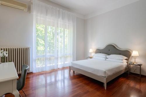 a white bedroom with a bed and a large window at Room & Breakfast D'Annunzio in Ravenna