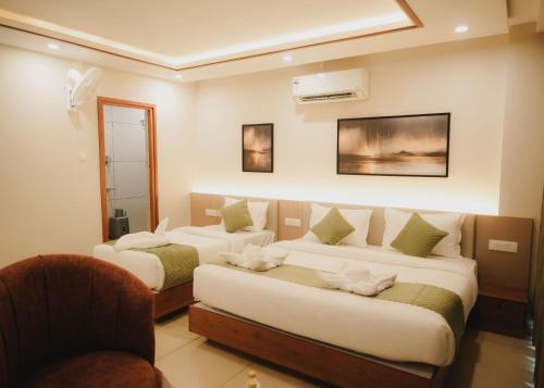 a hotel room with two beds and a chair at Hotel Calicut Beach-Silk Street in Kozhikode