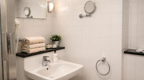 a white bathroom with a sink and a mirror at Hotel Am Weberplatz in Dresden
