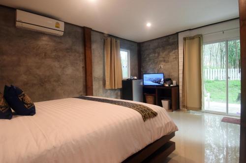 a bedroom with a bed and a tv and a window at BaanPhong Lanta in Ko Lanta