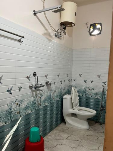a bathroom with a toilet and birds on the wall at Meeraj Residency in Mātigara