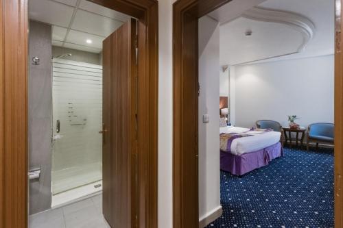 a bedroom with a bed and a walk in shower at Saraya Al Deafah Hotel in Mecca