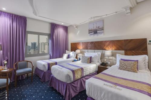 a hotel room with two beds and purple curtains at Saraya Al Deafah Hotel in Mecca