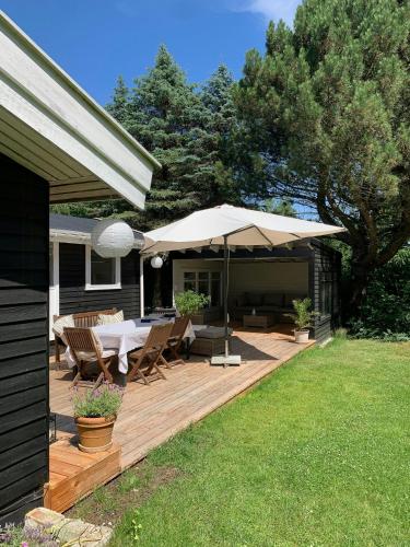 a wooden deck with a table and an umbrella at Charming Beach Cottage In Gilleleje in Gilleleje