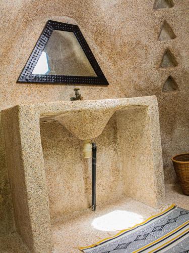 a bathroom with a stone sink and a mirror at La Maison Chocolat in Nianing