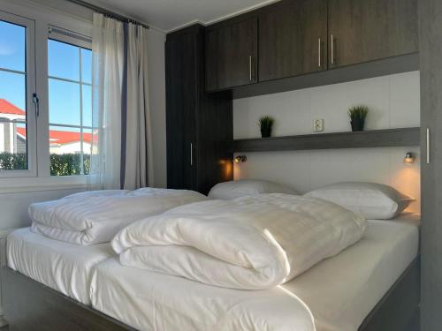 a bedroom with two beds with white sheets and a window at Chaletverhuur-Olmenduin in Serooskerke
