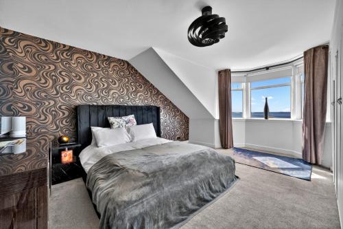 a bedroom with a large bed and a large window at Finest Retreats - Seamill Beach House in Seamill