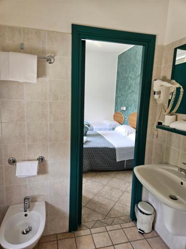 a bathroom with a sink and a toilet and a bed at Hotel Cerrano in Silvi Marina