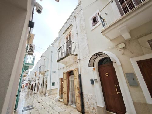 an alley with white buildings and a brown door at Olympus Luxury Suites Menotti in Mola di Bari
