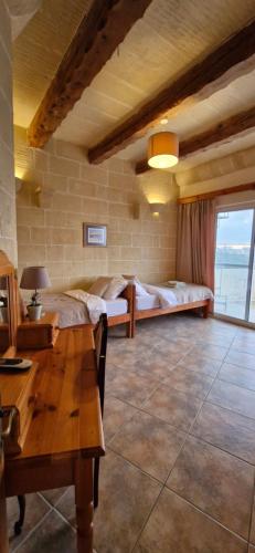 a living room with two beds and a table at Sunset Castle House with Pool in Xagħra