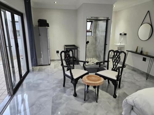 a bedroom with two chairs and a table and a bed at Cjabaledi Private Guesthouse in Centurion