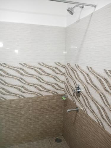 a shower with a wave pattern on the wall at Snow Range Cottages in Manāli