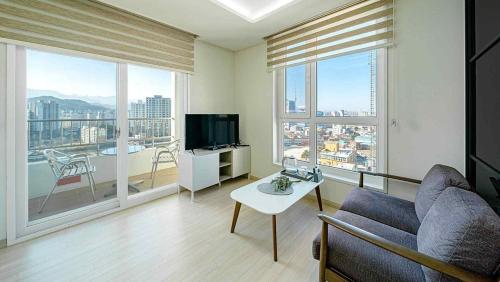 a living room with a couch and a tv and large windows at Sokcho Sono Residence in Sokcho