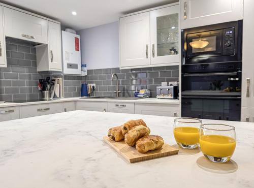 a kitchen with two glasses of orange juice and croissants at Sandlands - Perfect central location in Ryde