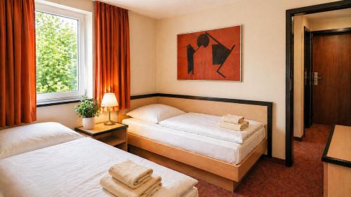 a hotel room with two beds and a window at Hotel Am Weberplatz in Dresden