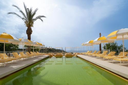 ein Schwimmbad mit Liegestühlen und Sonnenschirmen in der Unterkunft Doryssa Lithos Hotel in Pythagoreio