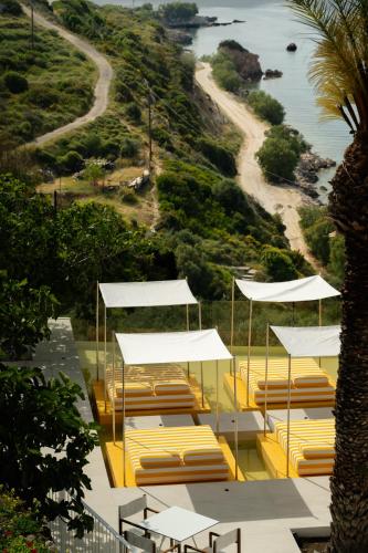 eine Gruppe von Liegestühlen und Sonnenschirmen an einem Strand in der Unterkunft Doryssa Lithos Hotel in Pythagoreio