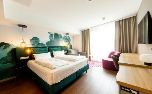 a hotel room with a bed and a living room at DORMERO Hotel Freiburg in Freiburg im Breisgau